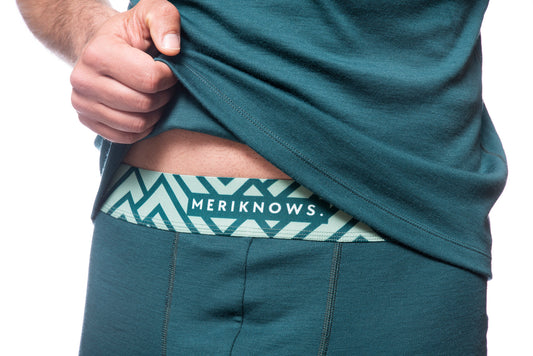 Person wearing a teal shirt with a visible brand logo on a white background