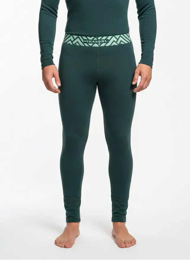 Person wearing green thermal merino wool leggings with a visible brand logo on a white background