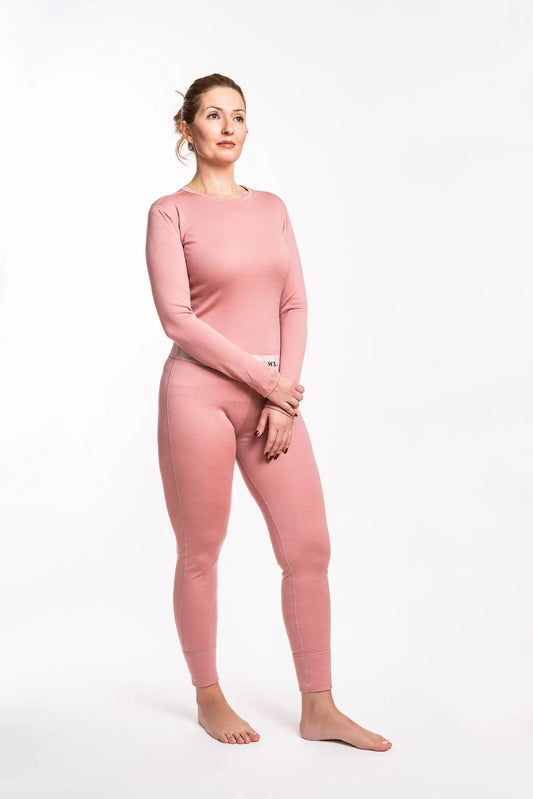 Woman wearing a pink merino long-sleeve top and pants on a white background