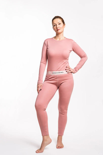 Woman wearing a pink long-sleeve merino top and pants on a white background