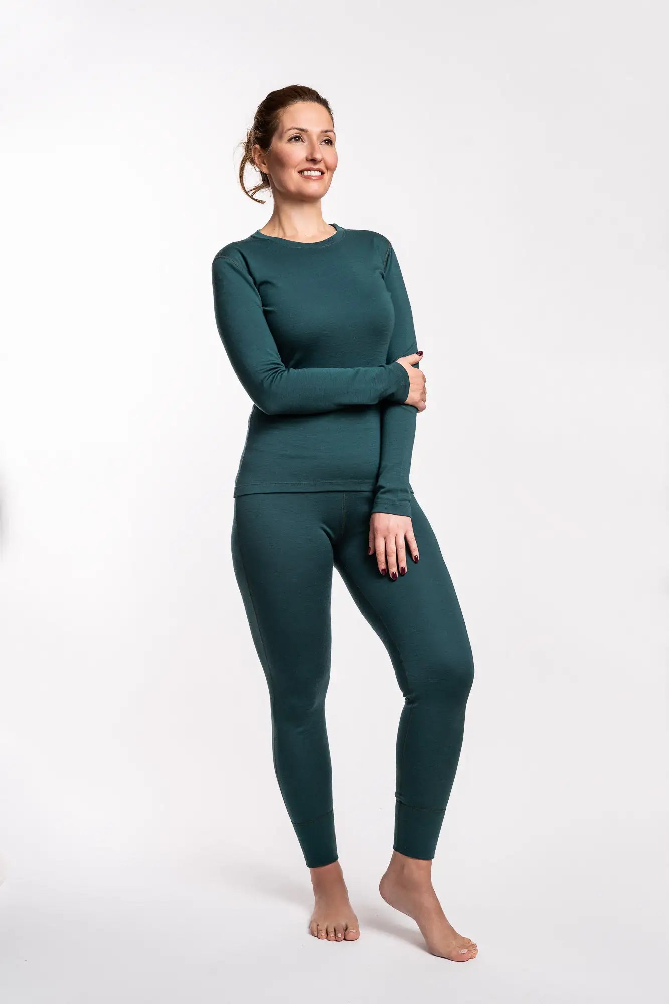 Woman wearing a green merino wool long-sleeve top and leggings on a white background