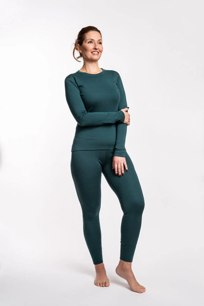 Woman wearing a green merino wool long-sleeve top and leggings on a white background