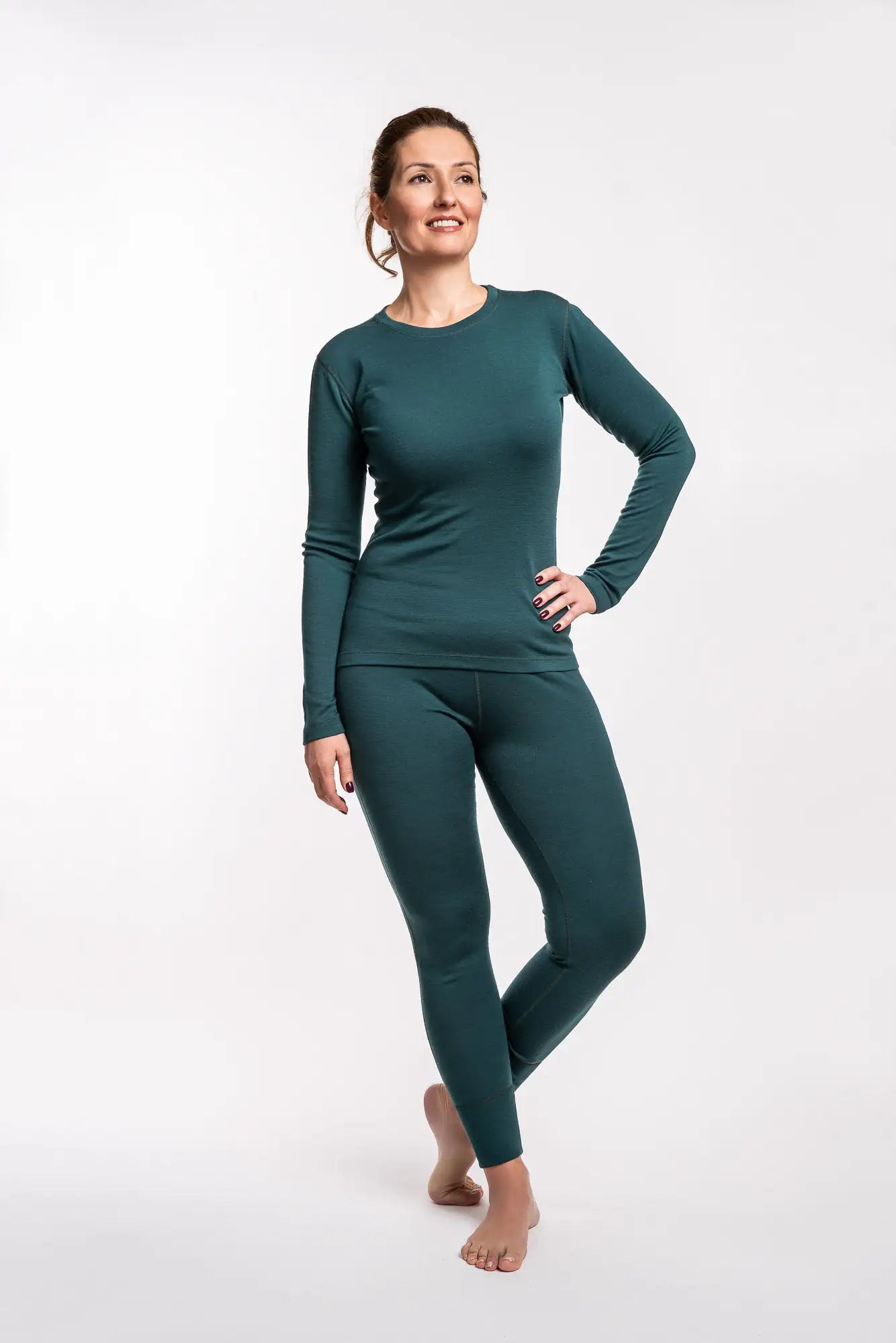 Woman wearing a teal merino long-sleeve top and leggings on a white background